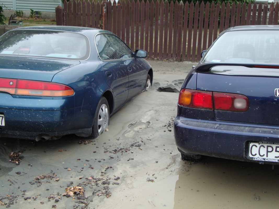 Two cars partly buried in silt caused by earthquake liquefaction