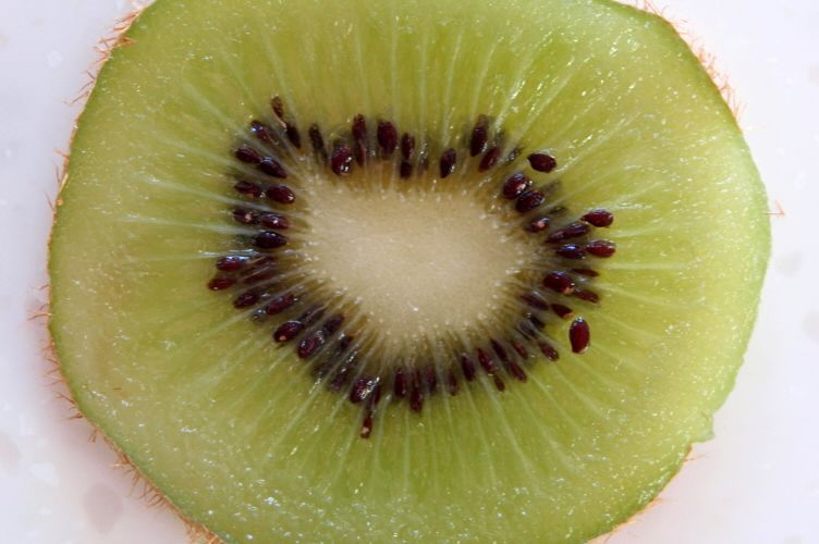 Green Kiwifruit sliced to show center with seeds.