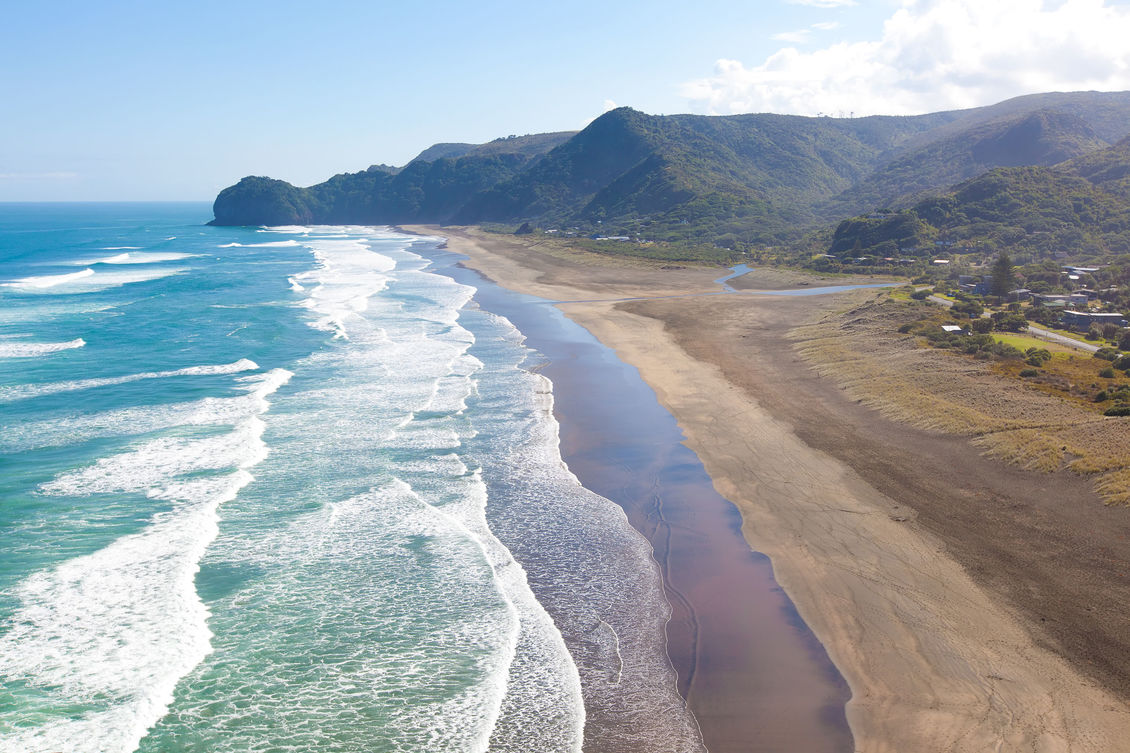 Ocean waves rolling onto the beach at Piha, New Zealand.