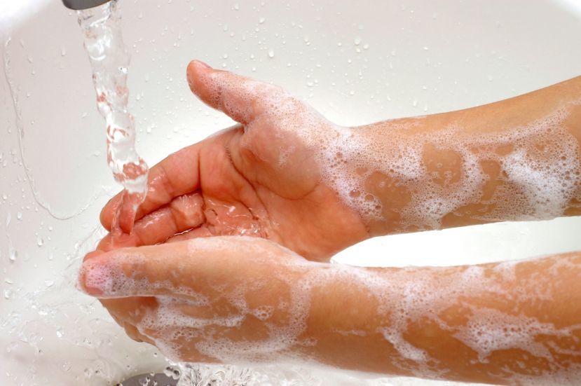 Washing hands in soapy water under a tap of running water.