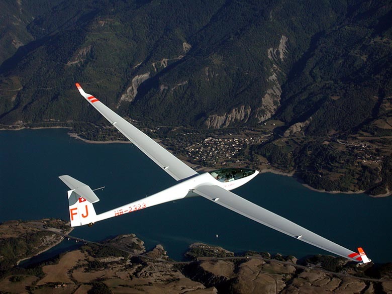 Single-seat fiberglass glider flying over French Alps.