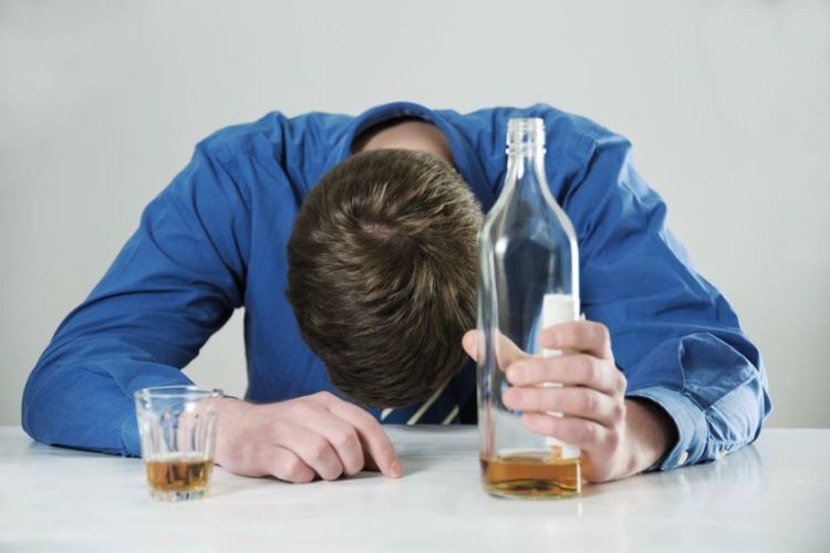 Man slumped over table with glass holding bottle=Alcohol abuse