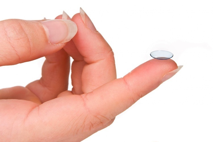 Soft contact lens on tip of a finger with white background