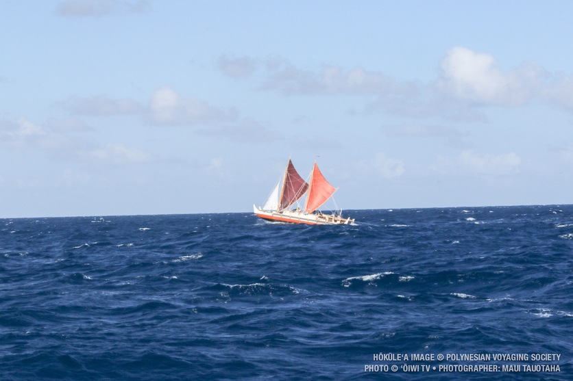 A Waka in ocean swell, blue skies.