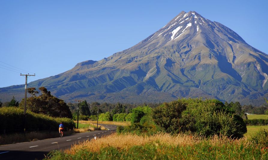 View of Mount Taranaki, New Zealand with road in foreground. 