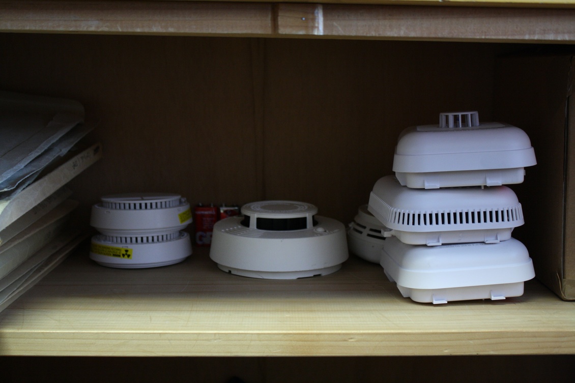 Variety of smoke detectors in an office cupboard.