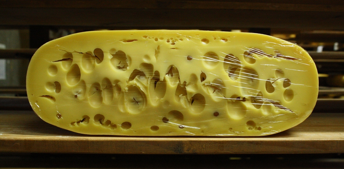 Halved Meyer Gouda Cheese’s Maasdam cheese on a shelf.