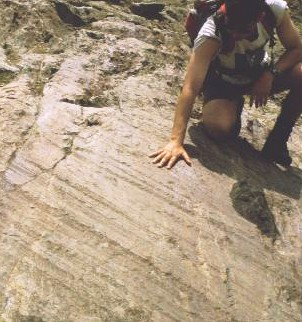 Scientist with hand on freshly exposed striations on rock. 
