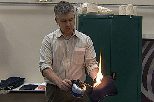 Dr Stewart Collie demonstrating a fabric's flame resistance