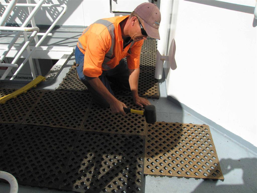 Steve Bailey laying down rubber mats on ship's deck.