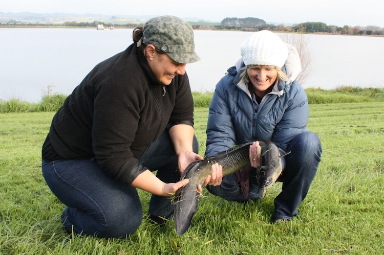 2 women holding a 60-year-old eel before releasing it into Lake