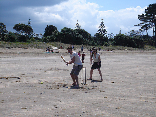Group of people playing beach cricket in New Zealand.