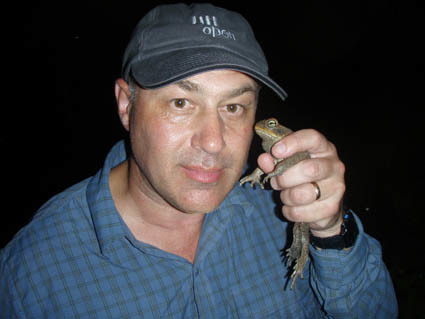 Dr Phil Bishop in a cap holding a frog at nighttime.