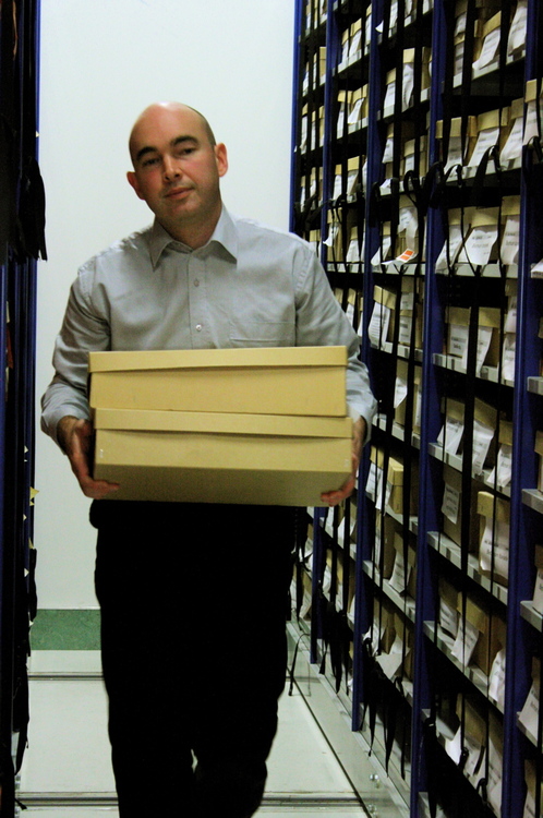 Dr Leon Perrie holding 2 boxes in Te Papa Museum’s herbarium