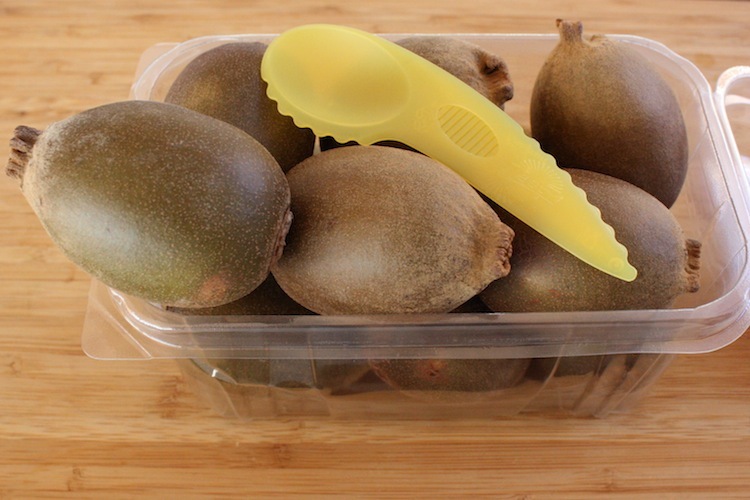 Kiwifruit in a plastic pack with a yellow spife on top.