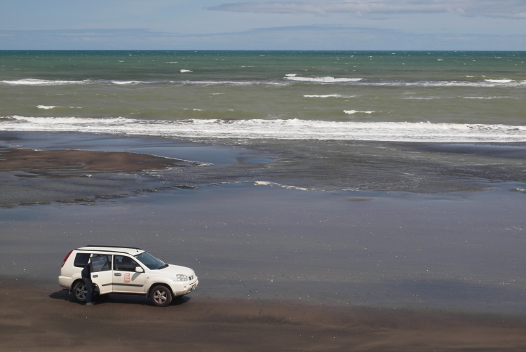 paleontologist with car on a beach