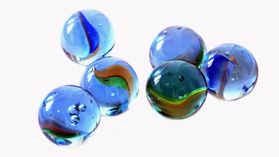 6 marbles, mainly blue coloured on a pale background.