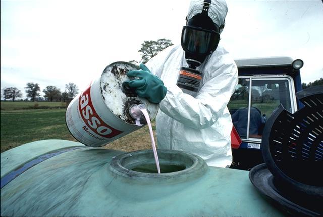 Organochlorines crop pesticide. Person in a hazmat suit.
