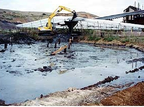 A digger removing sludge from pool, Rotowaro Carbonisation Plant