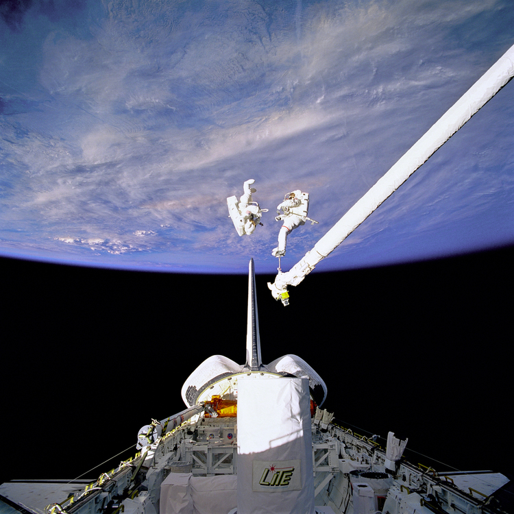 Two astronauts outside the Space Shuttle with Earth behind them