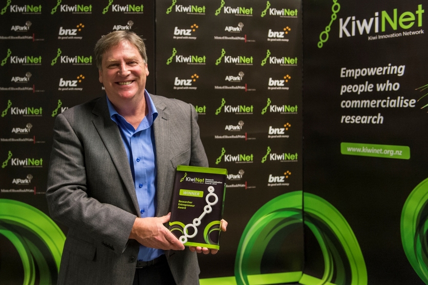 Alistair Jerrett holding award at the 2014 KiwiNet Awards.