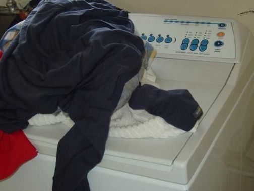 Pile of laundry on a washing machine.