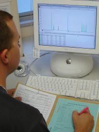 Forensic scientist analysing a DNA profile at computer.