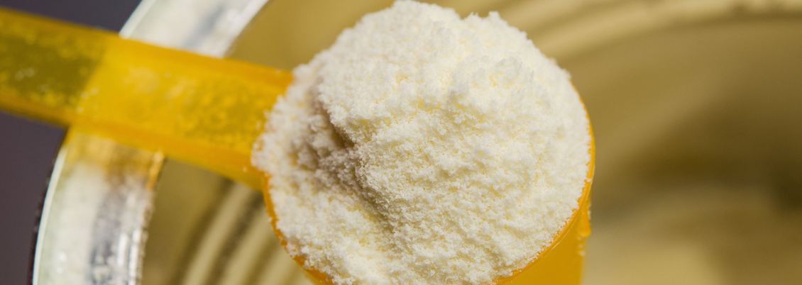 Close up of yellow scoop of infant milk formula.