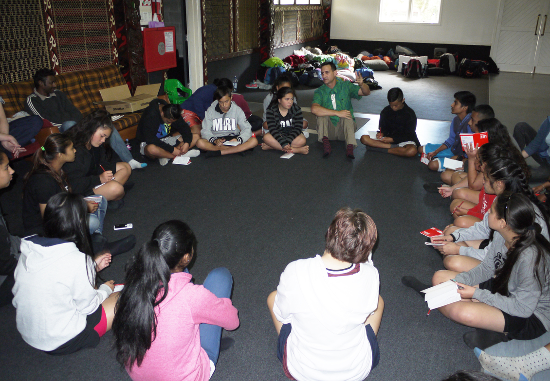 Group of students sitting in a circle at Makaurau Marae, NZ.