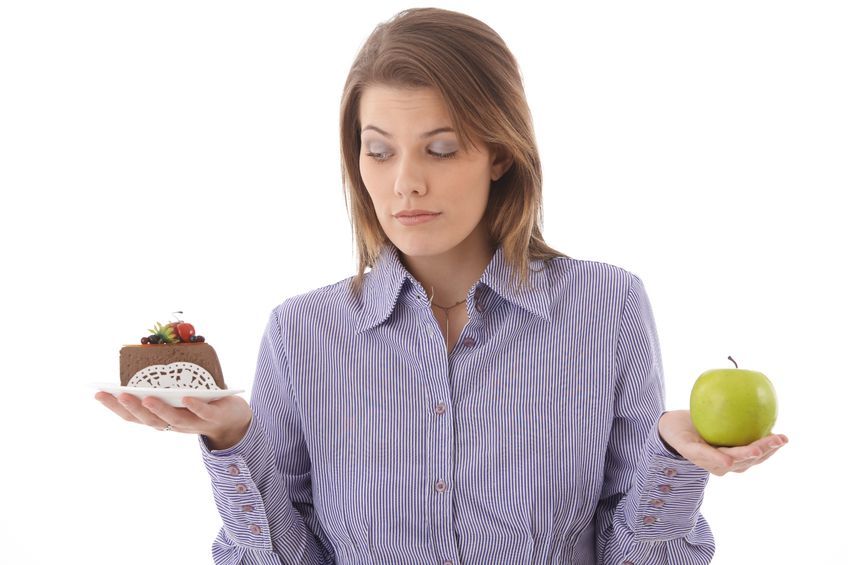 Woman holding a cake in left hand and green apple in right hand