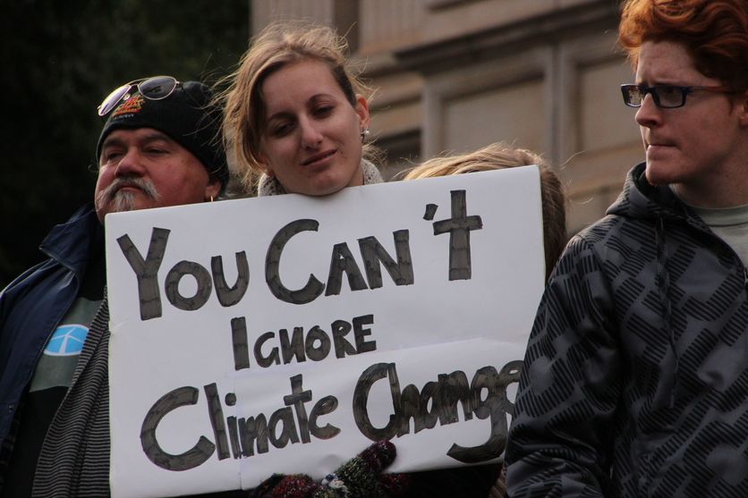 Woman holding 'You can’t ignore climate change ' sign at protest