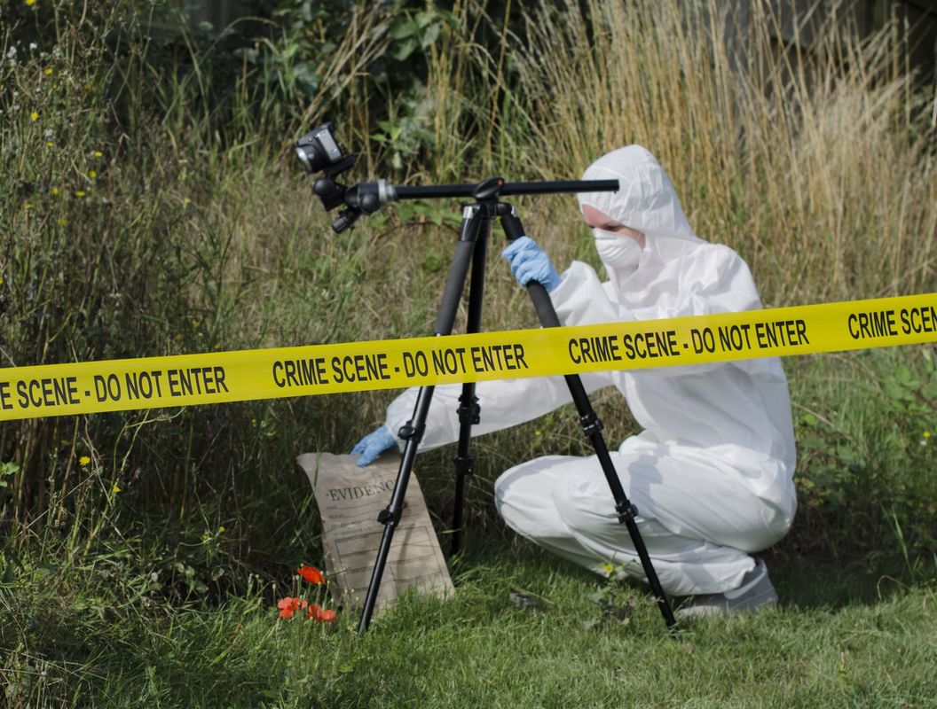Scientist in forensic suit with camera outside investigating.