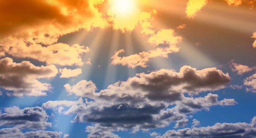 Sun rays through a blue cloudy sky