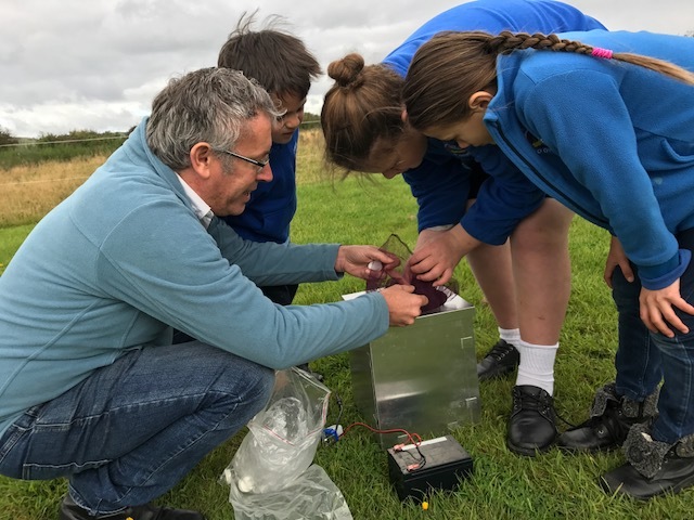 Scientist and students check the contents of a Heath moth trap.