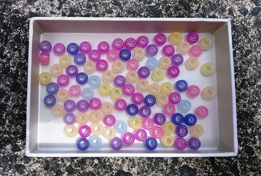Silver tray of coloured UV beads.