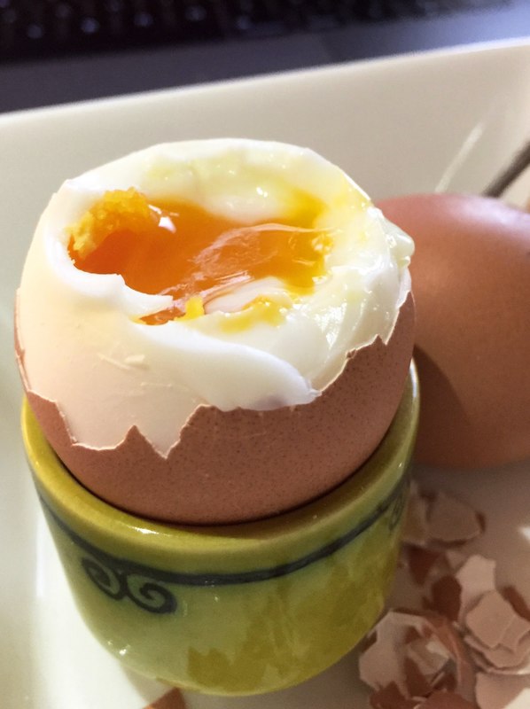 Soft boiled egg cracked open in an egg cup.