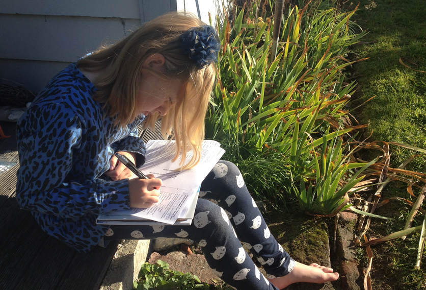 Young female student recording bird species in their garden.