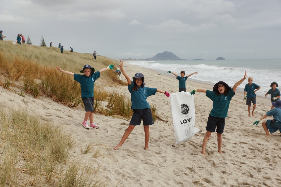 School children taking part in a beach clean up and celebrating.