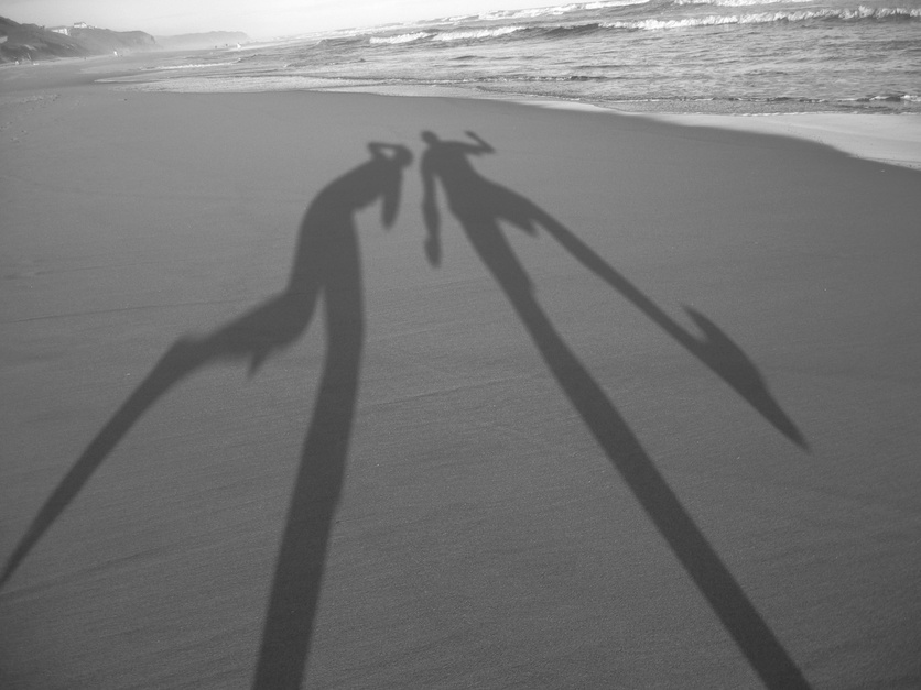 Long shadows on a beach of two people. 