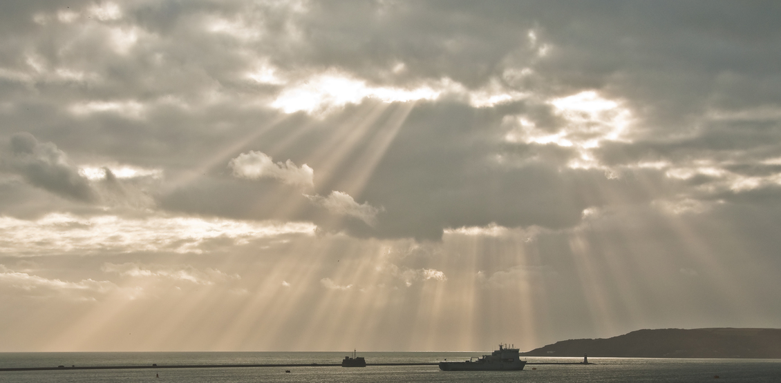 Crepuscular rays spreading out from the sun over Plymouth Sound