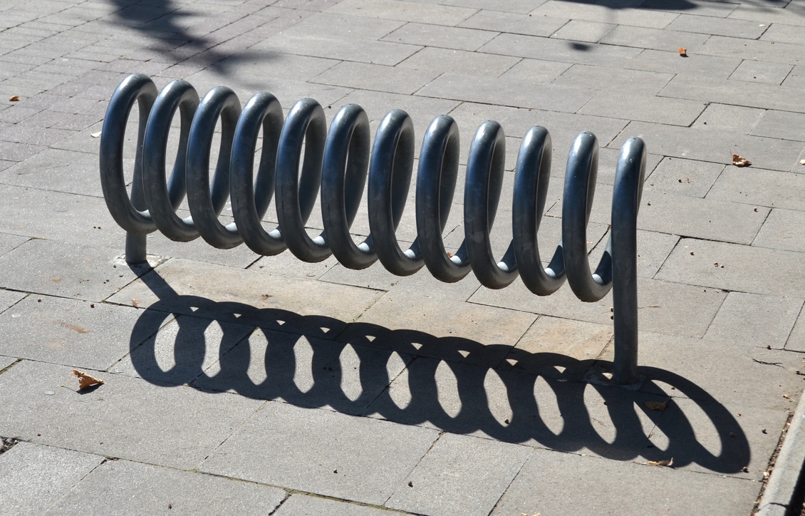 Shadows cast by a coiled bicycle rack.