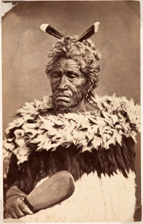 19th century photo of Māori man with a kahukurī & holding a patu