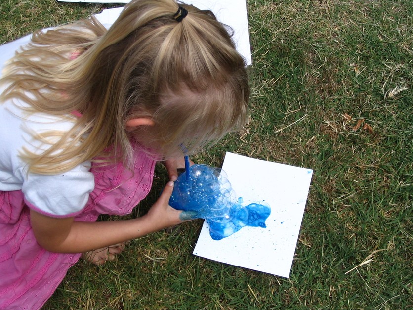 Young girl with blue bubble experiment outside.