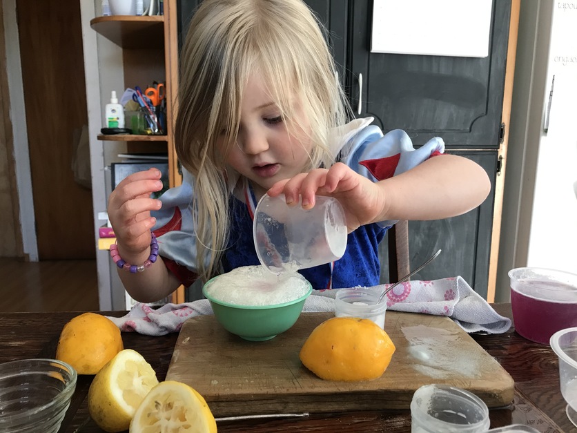 Young blond girl experimenting with baking soda and lemon juice.