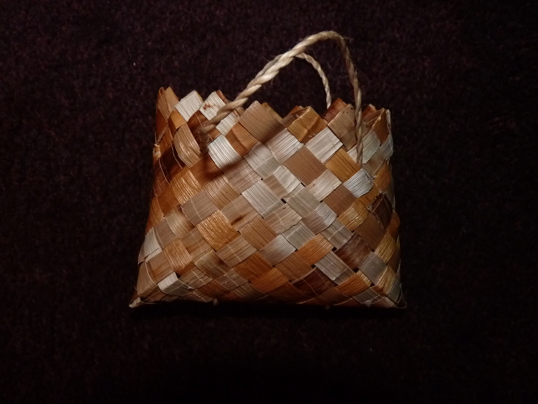 A small kete (basket) made with split kuta on black background