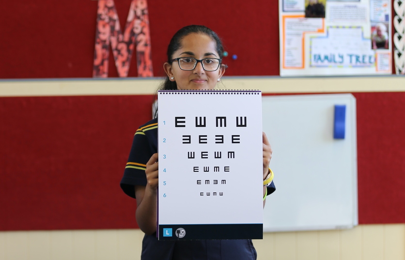Student holding a high-contrast eye test vision chart.