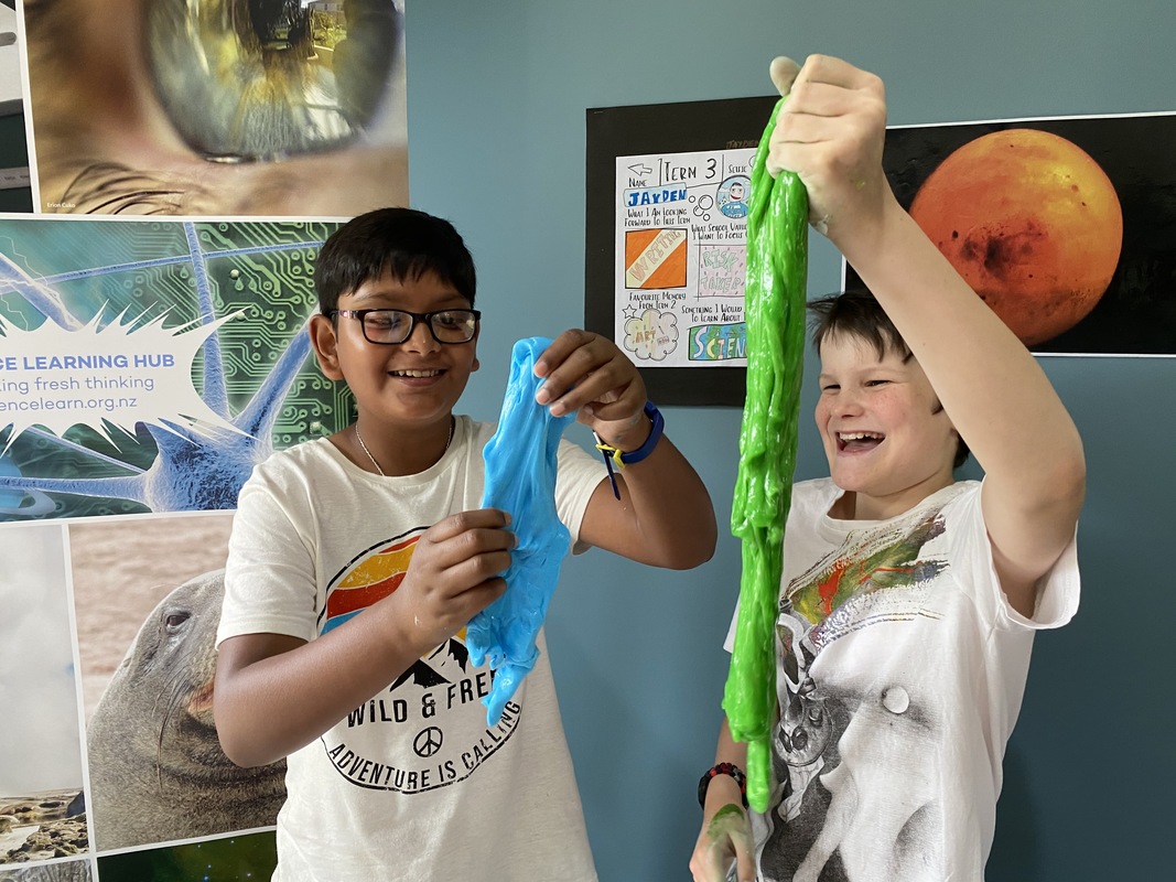 Two young boys enjoying playing with blue and green slime.