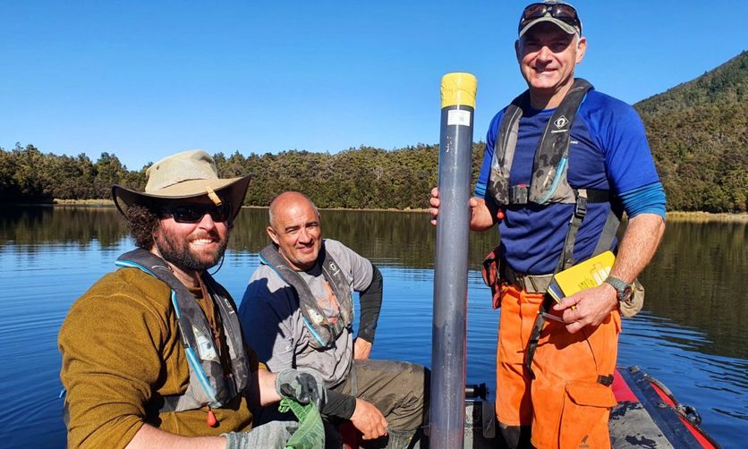 Scientists in a boat holding a sediment core from the lake.