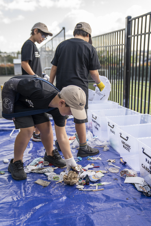 Three boys sort litter into plastic containers.