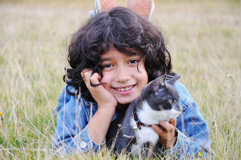 Child with cat in field